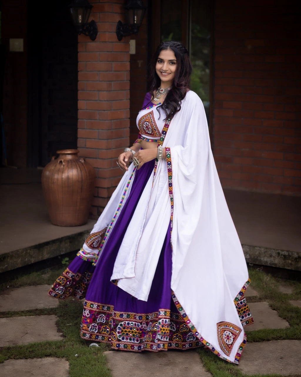 Woman in traditional outfit with a white dupatta standing outdoors.