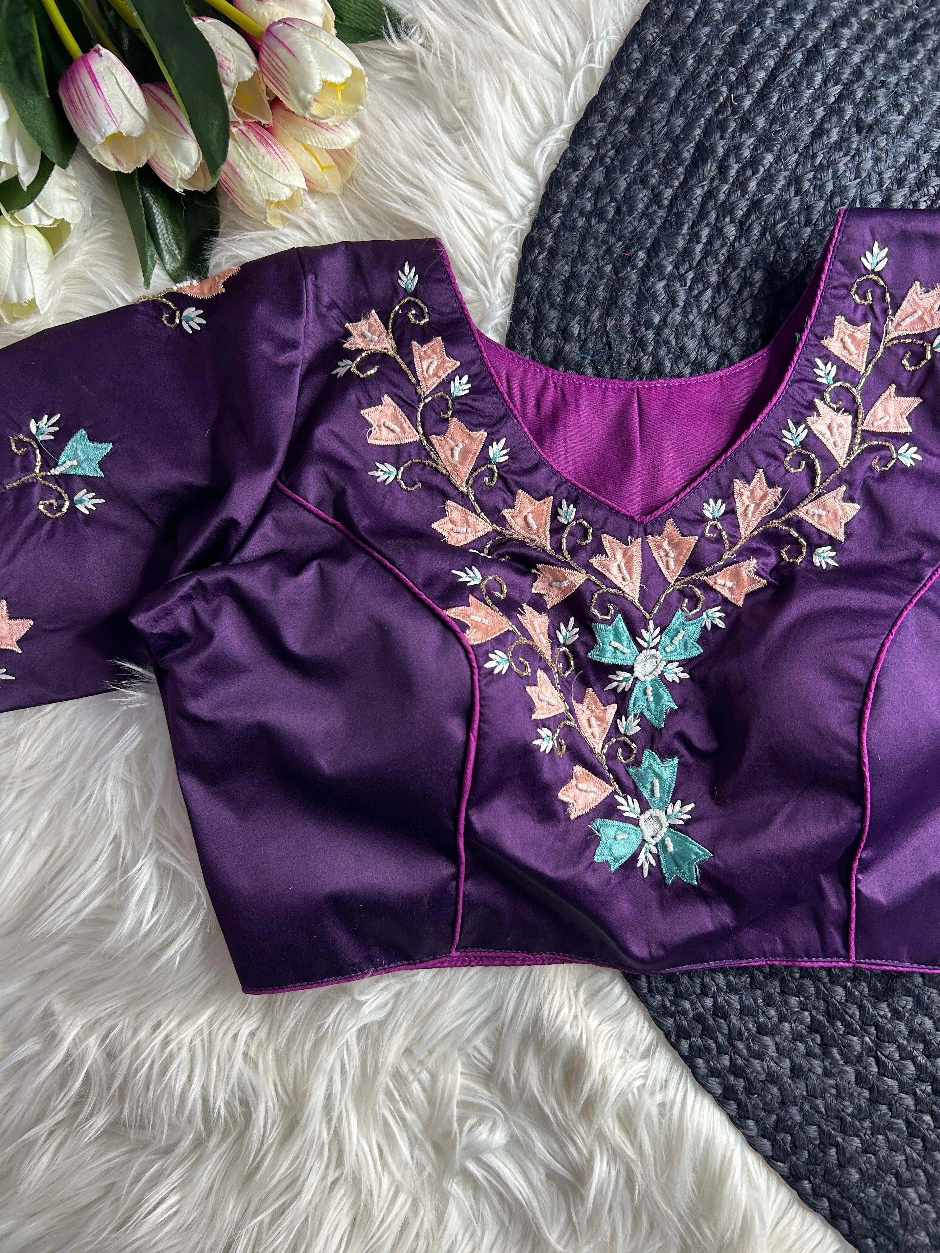 Purple blouse with floral embroidery on a textured surface with tulips in the background