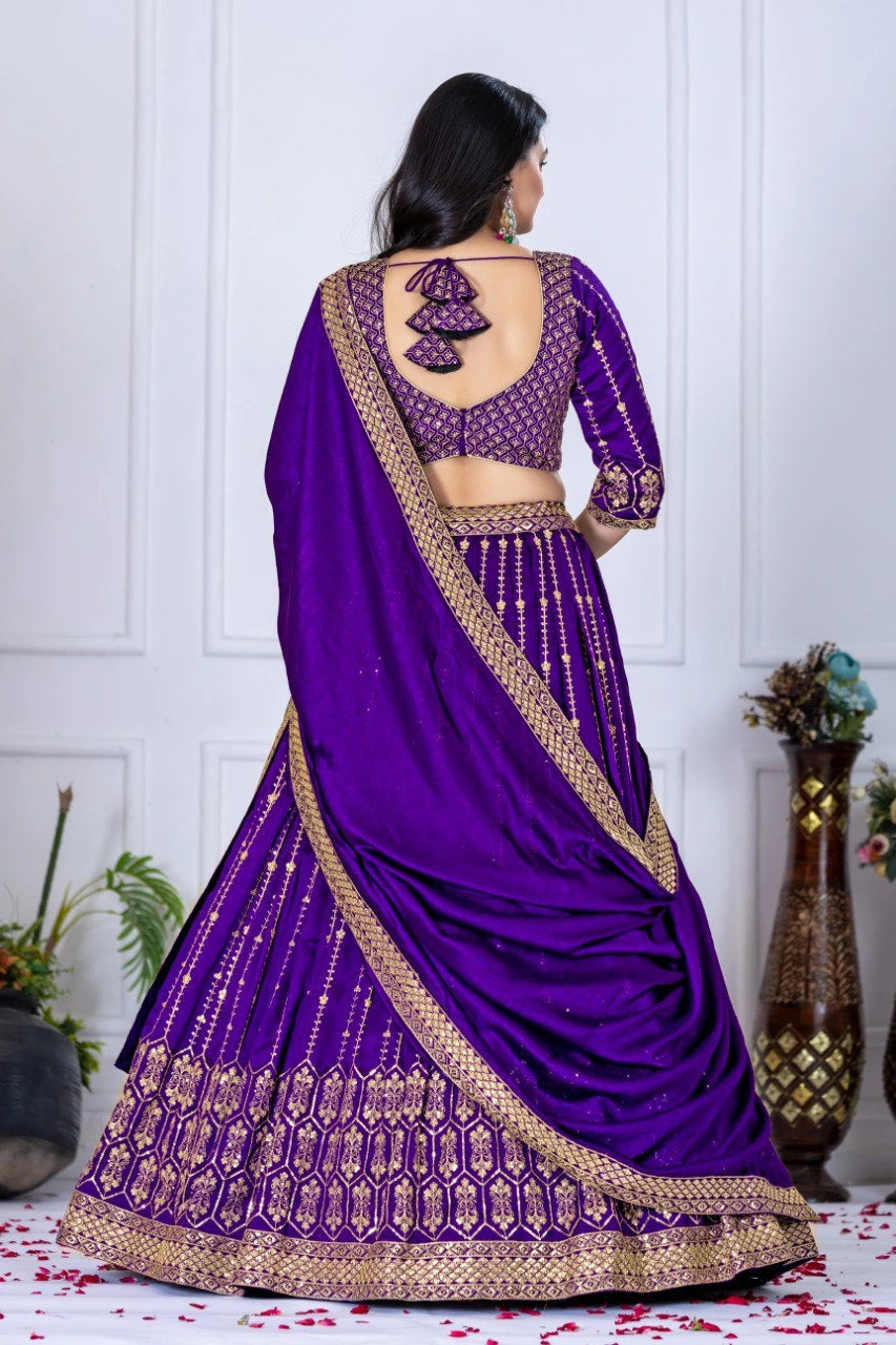 Purple saree with gold border worn by a model against a white paneled wall.