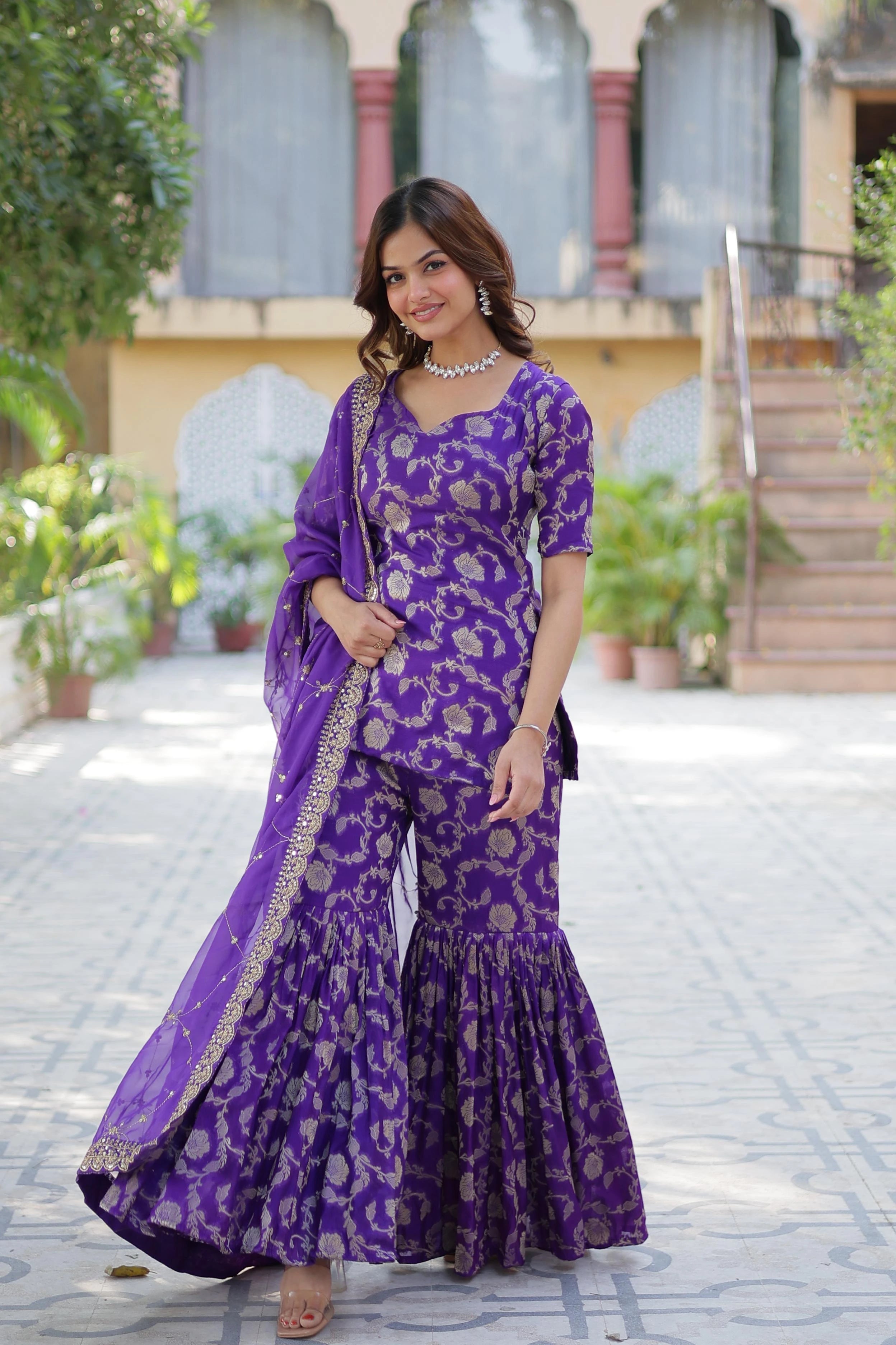 Woman in a purple traditional outfit standing outdoors.