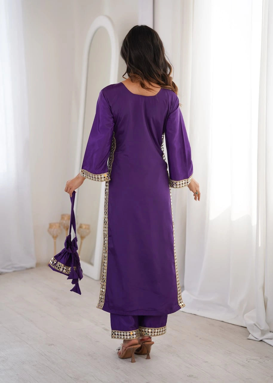 Woman in a purple outfit with gold trim standing in front of a mirror.