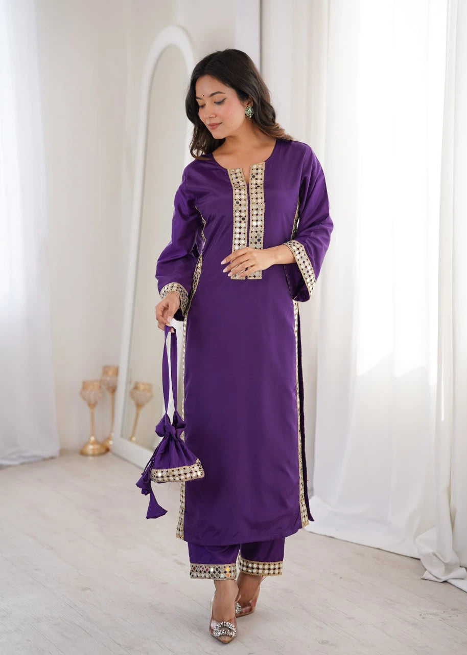 Woman wearing a purple traditional outfit with gold embroidery in a white room.