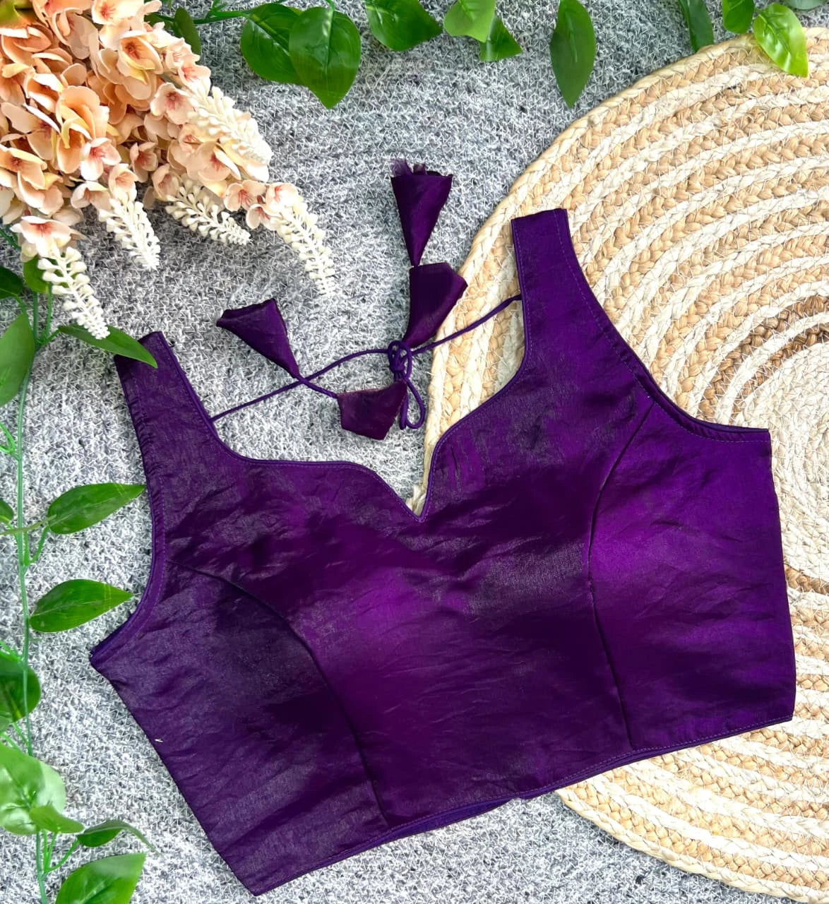 Purple bikini set on a textured surface with flowers and leaves.