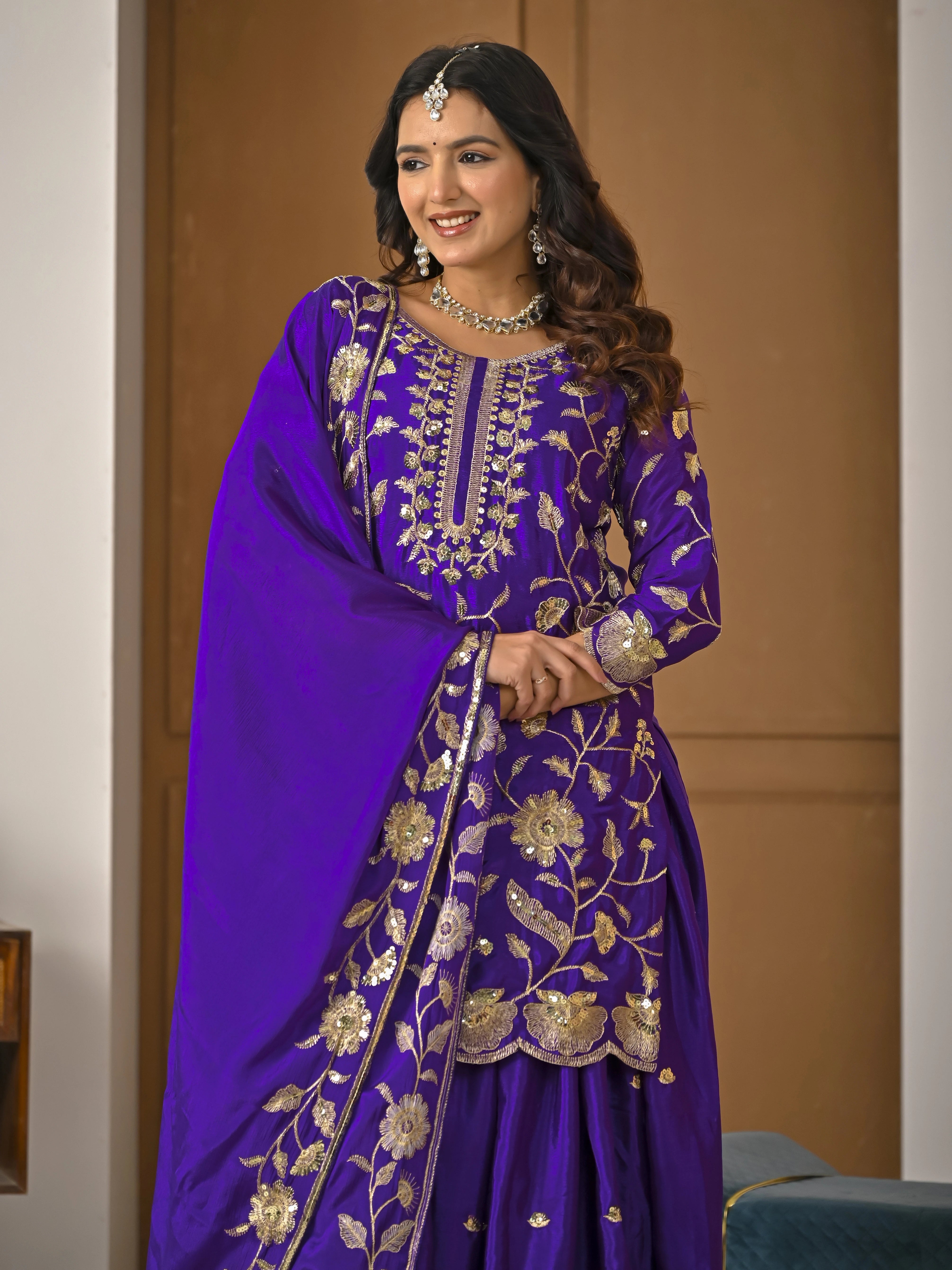 Woman wearing a purple embroidered traditional outfit indoors.