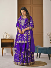 Woman wearing a purple embroidered traditional outfit in a room setting.