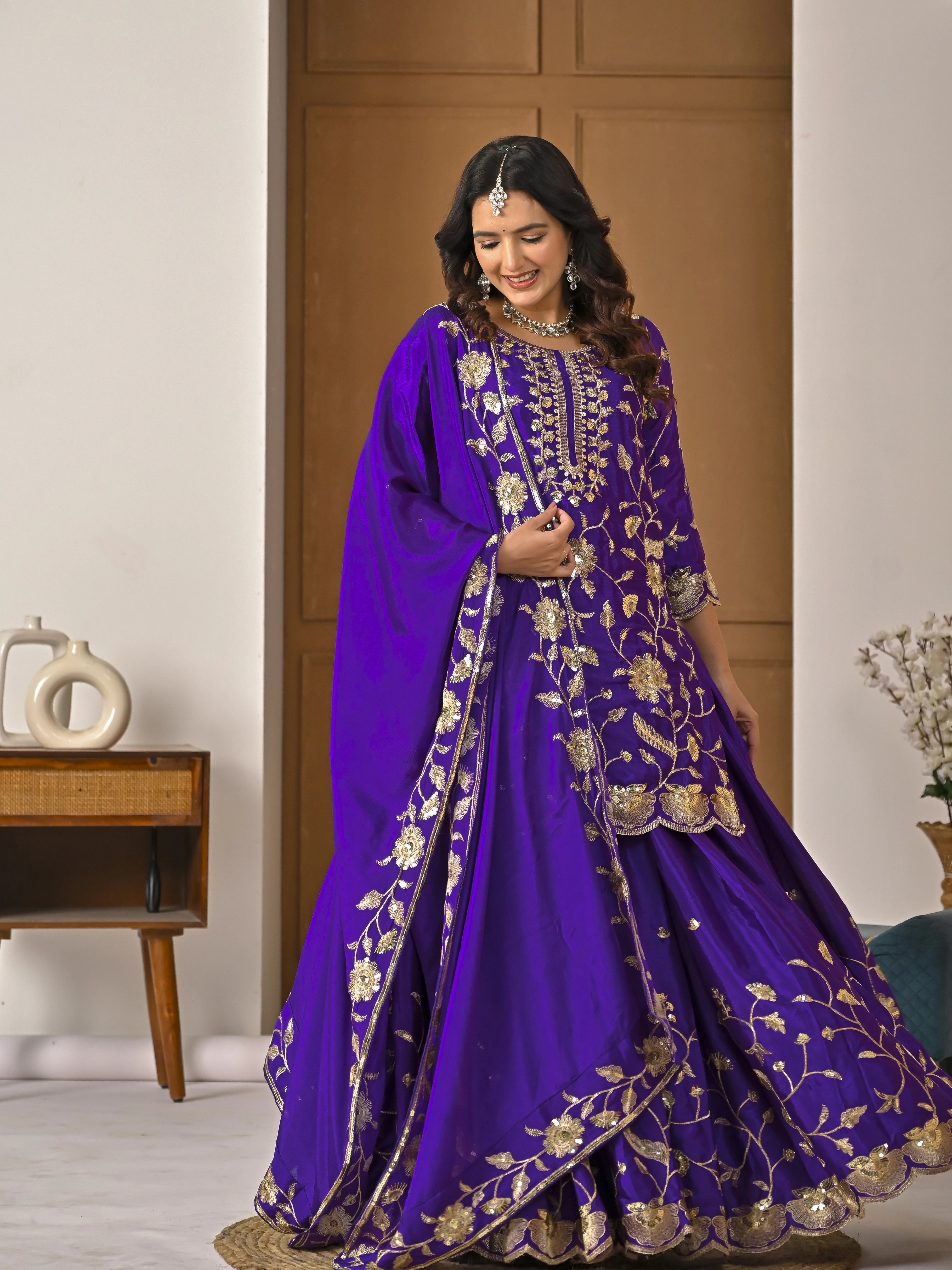 Woman wearing a purple embroidered traditional outfit indoors.