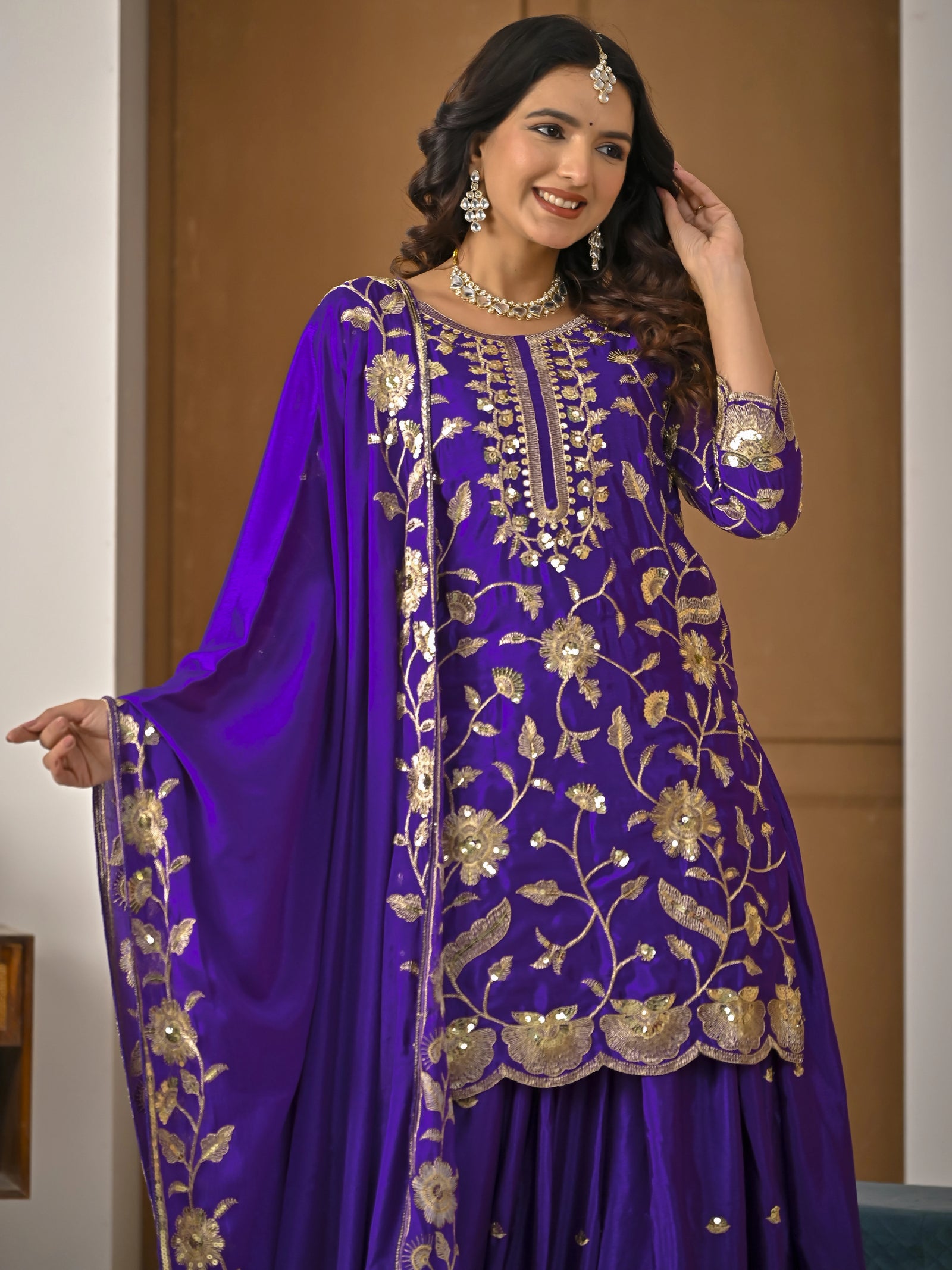 Woman wearing a purple embroidered traditional outfit with gold details.