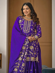 Woman wearing a purple embroidered traditional outfit indoors.