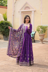 Woman in a purple traditional outfit standing outdoors with decorative elements in the background