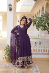 Woman in a purple traditional outfit standing in a decorative indoor setting.