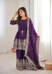 Woman in a purple traditional outfit with white embroidery standing in a bright room.