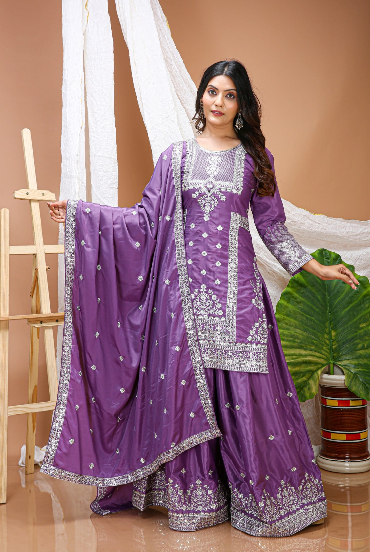 Woman wearing a purple traditional outfit with white embroidery against a beige background