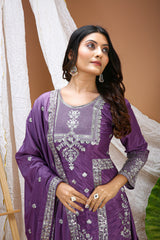 Woman wearing a purple traditional outfit with silver embroidery against a white curtain background