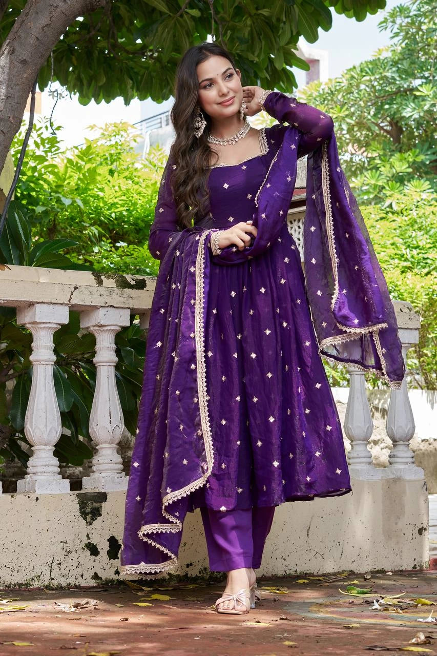 Woman in a purple traditional outfit with star patterns standing outdoors.