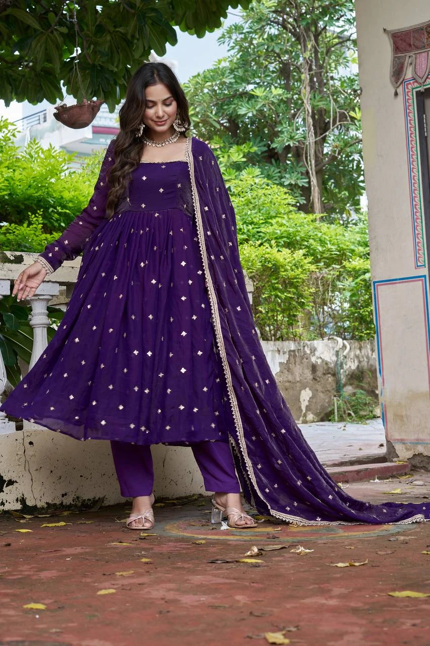 Woman wearing a purple traditional outfit with a long train in an outdoor setting.
