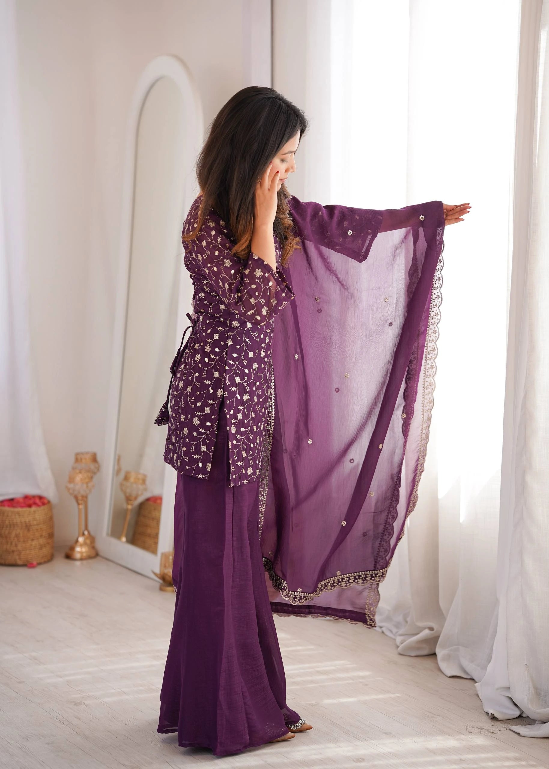 Woman in a purple outfit with a matching scarf in a room with white curtains.