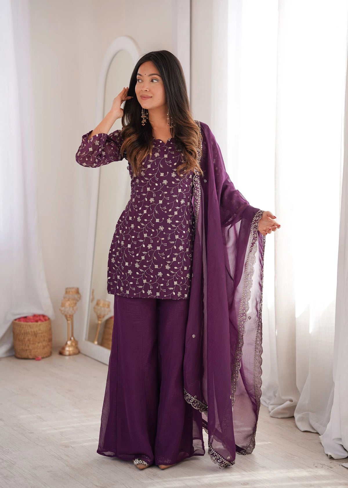 Woman in a purple traditional outfit with a matching dupatta in a well-lit room.