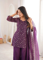 Woman wearing a purple traditional outfit with a matching dupatta in a bright room.