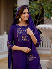 Woman wearing a purple embroidered outfit with a matching dupatta outdoors.