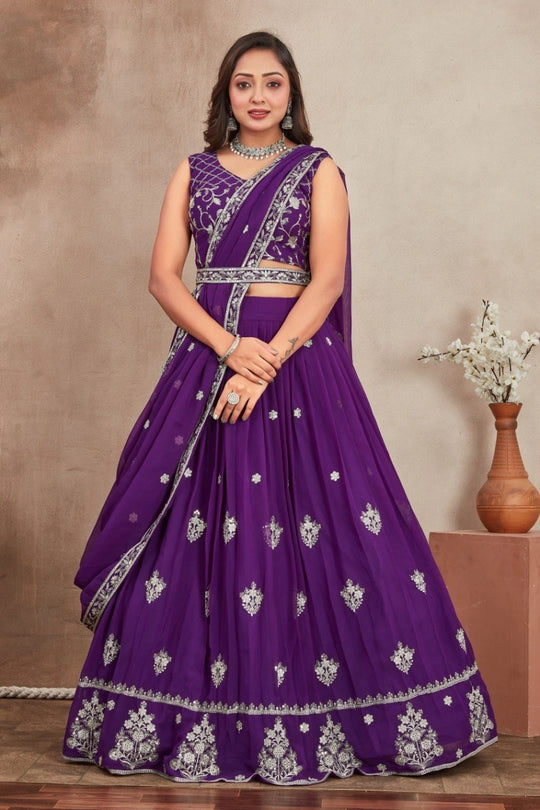 Woman wearing a purple embroidered saree with a neutral background