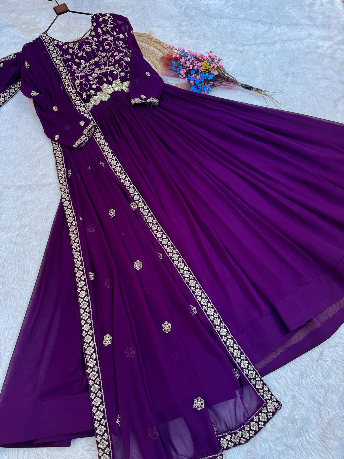 Purple traditional outfit with gold embroidery on a light gray background