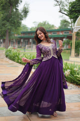 Woman in a purple traditional outfit standing outdoors with greenery in the background