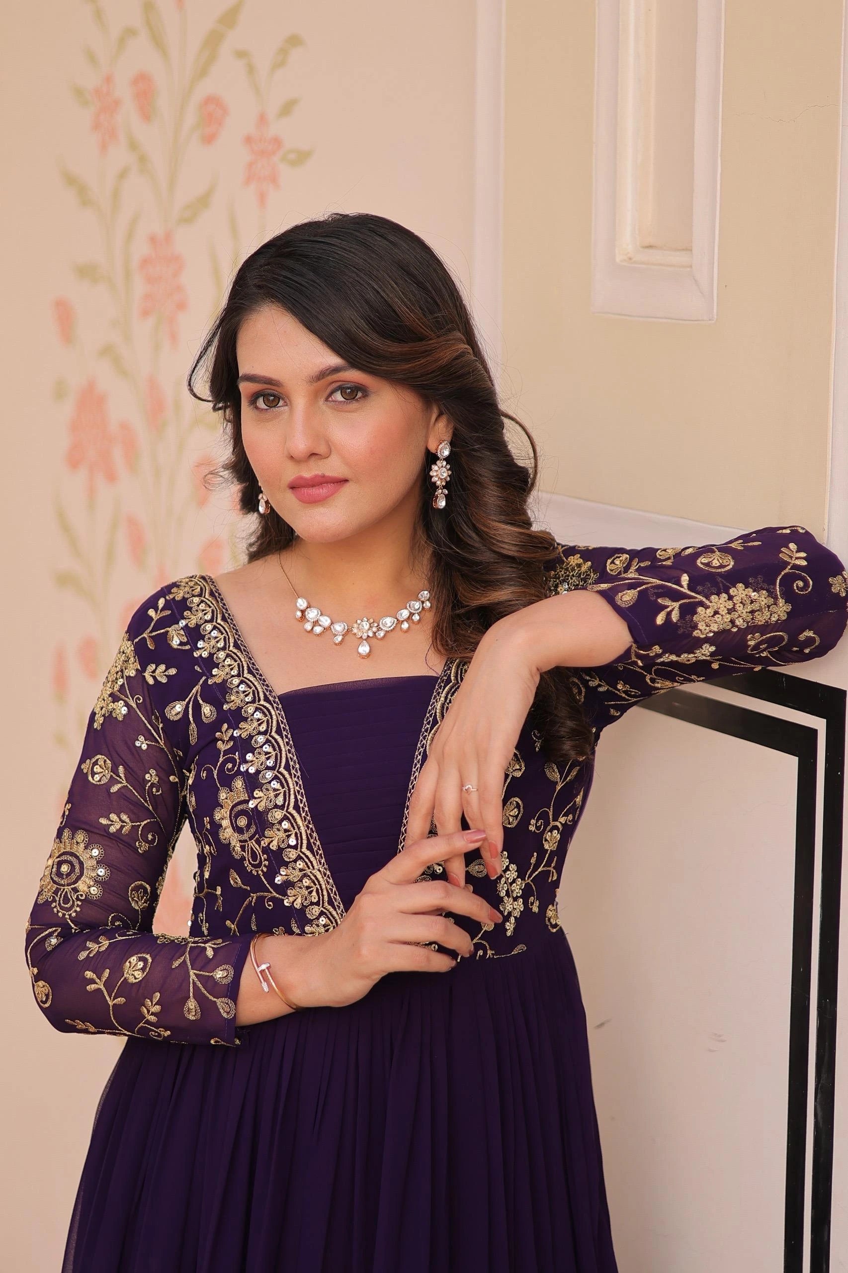 Woman wearing a purple dress with gold embroidery indoors.