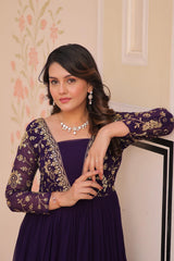 Woman wearing a purple dress with gold embroidery indoors.