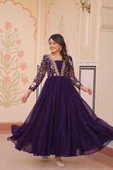Woman wearing a purple gown with floral embroidery in an indoor setting.