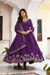 Woman wearing a purple traditional outfit with palm tree patterns in an indoor setting.