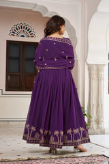 A rear view of the purple Anarkali suit, demonstrating the heavy pleating that creates its voluminous flare. The gold palm tree embroidery continues seamlessly around the entire base of the skirt.