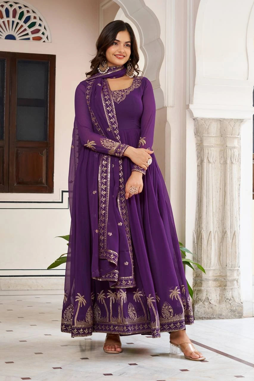 The woman stands centered in the frame, wearing the purple ensemble. The gold embroidery at the hemline is prominently displayed against the white marble floor.