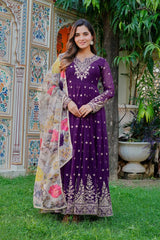 Woman in a purple traditional outfit with a floral shawl standing in a garden.