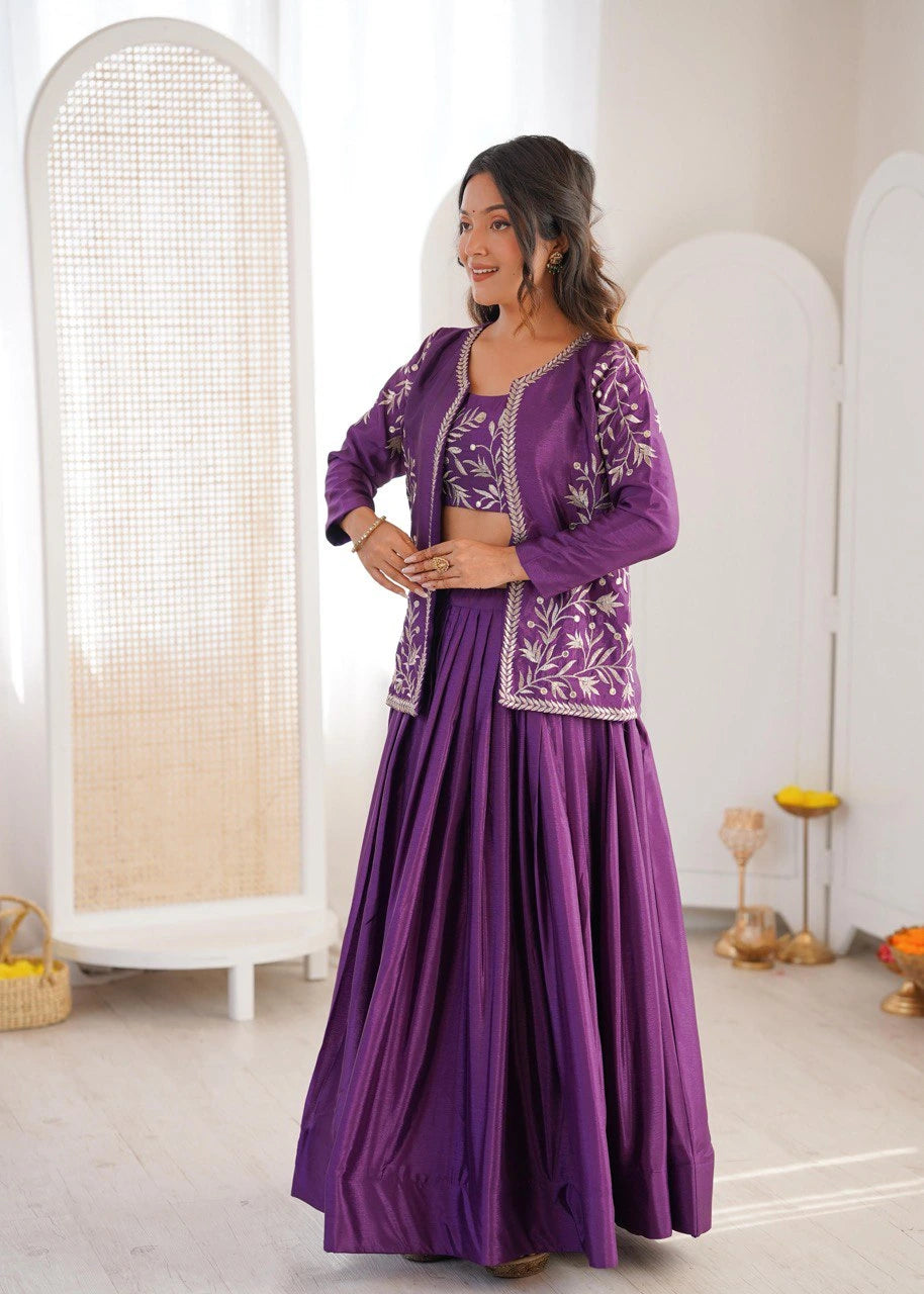 Woman in a purple traditional outfit with intricate designs standing in a bright room.