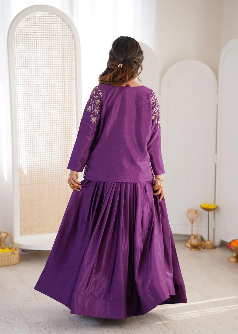 Woman wearing a purple dress with floral embroidery in a minimalistic room.