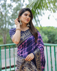 Woman wearing a purple saree with a green outdoor background