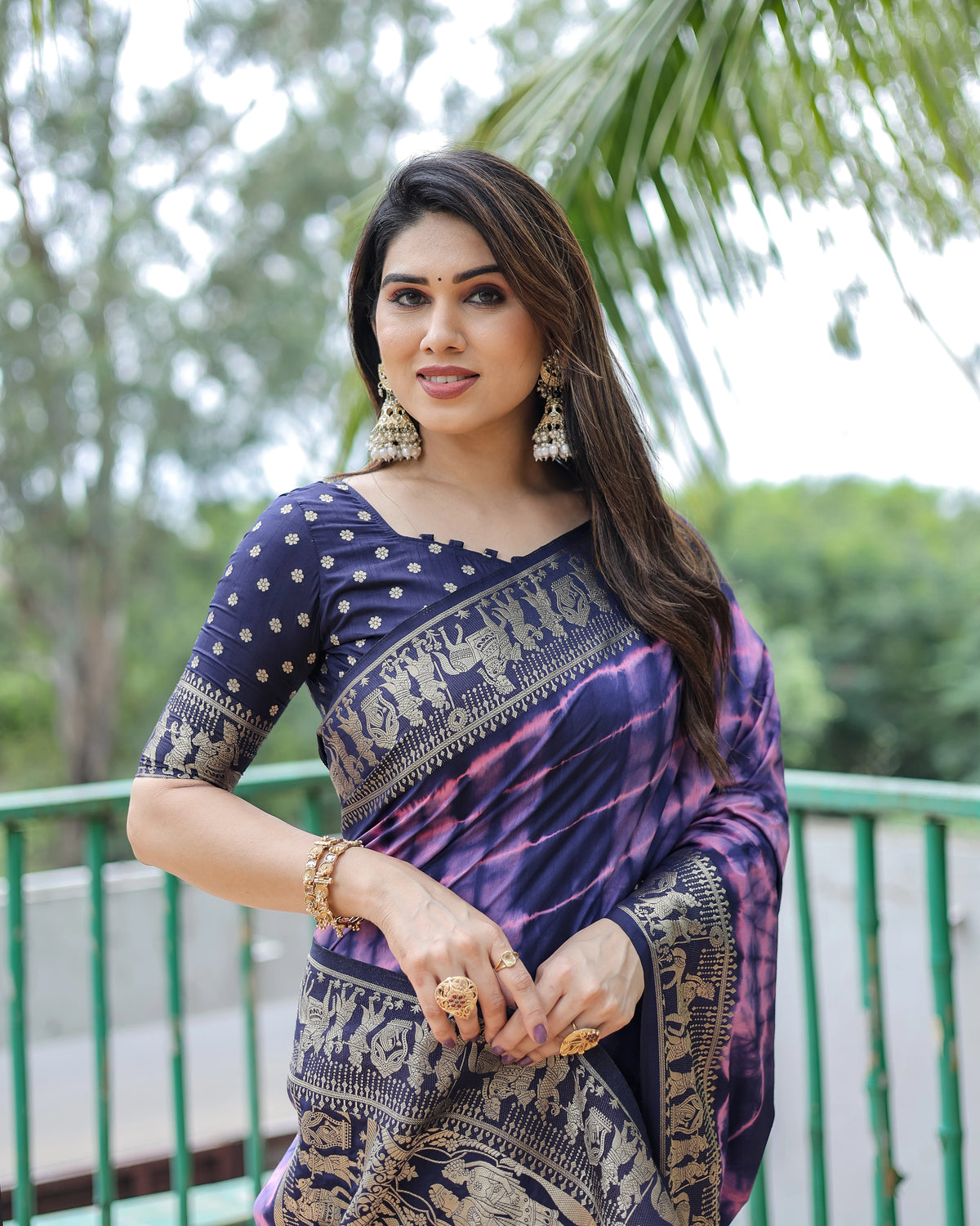 Woman wearing a traditional saree with a blurred green outdoor background