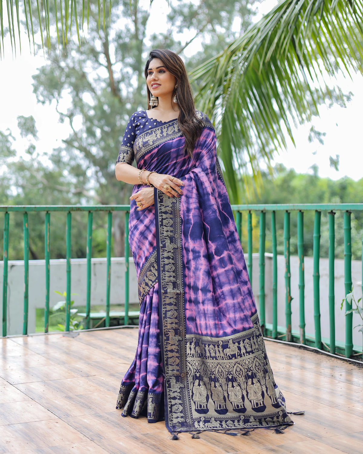 Woman wearing a purple and black saree with a scenic background