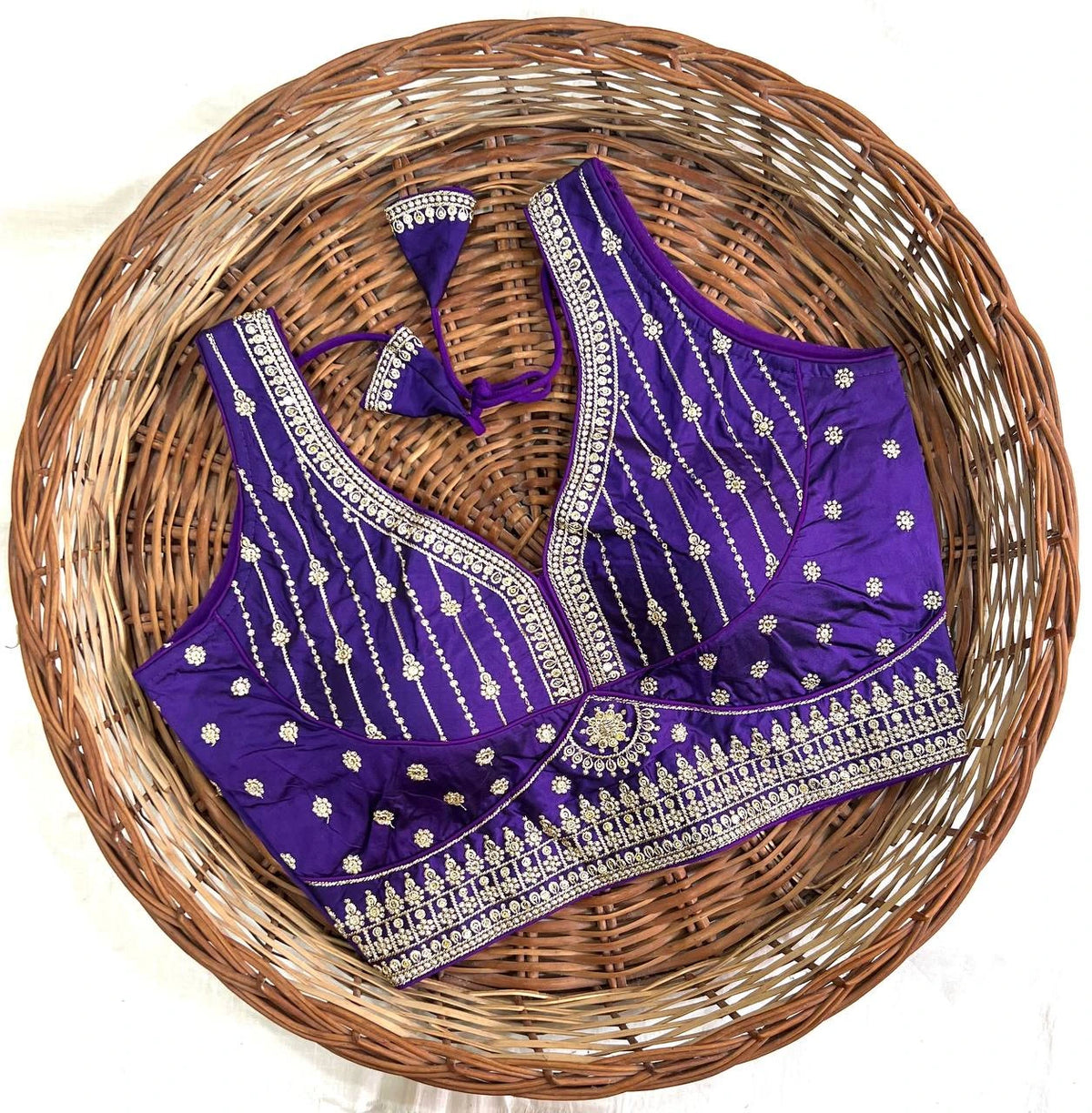 Purple embroidered blouse on a woven basket