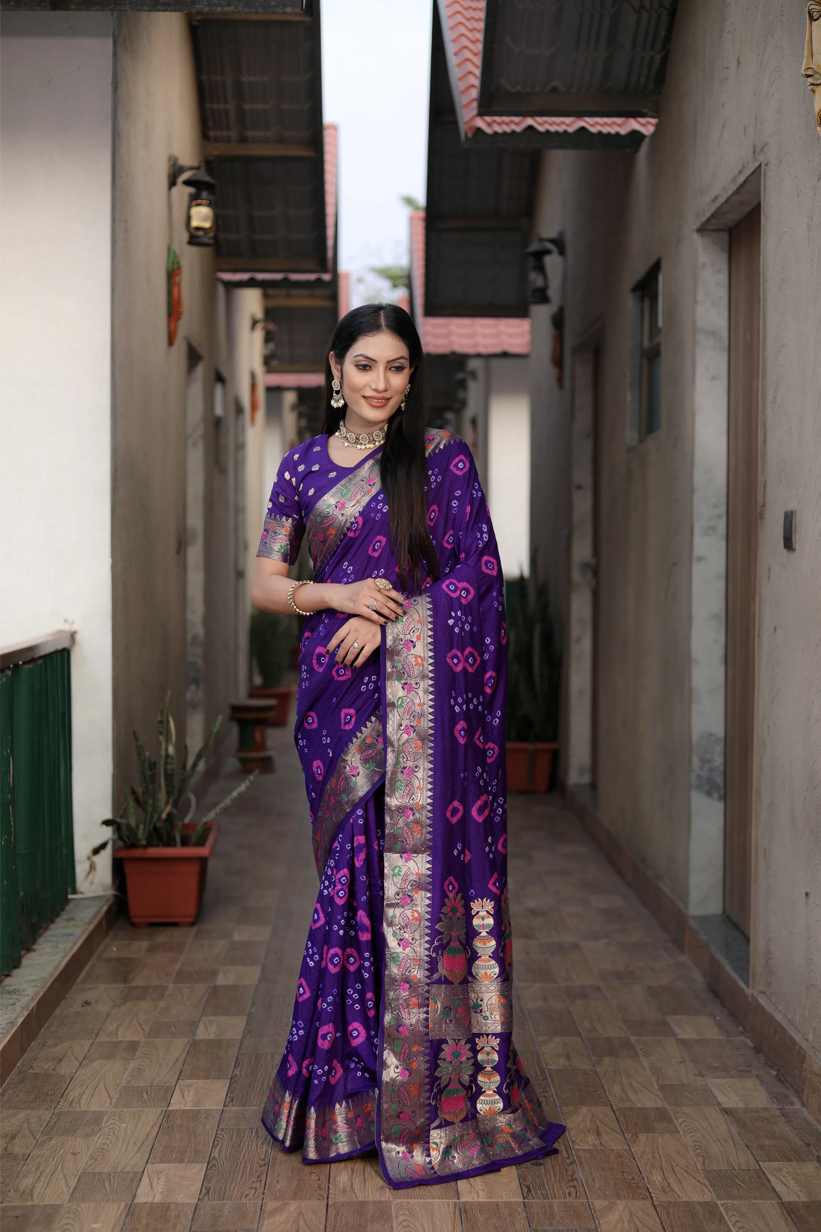 Woman in a purple saree walking down a narrow alleyway.