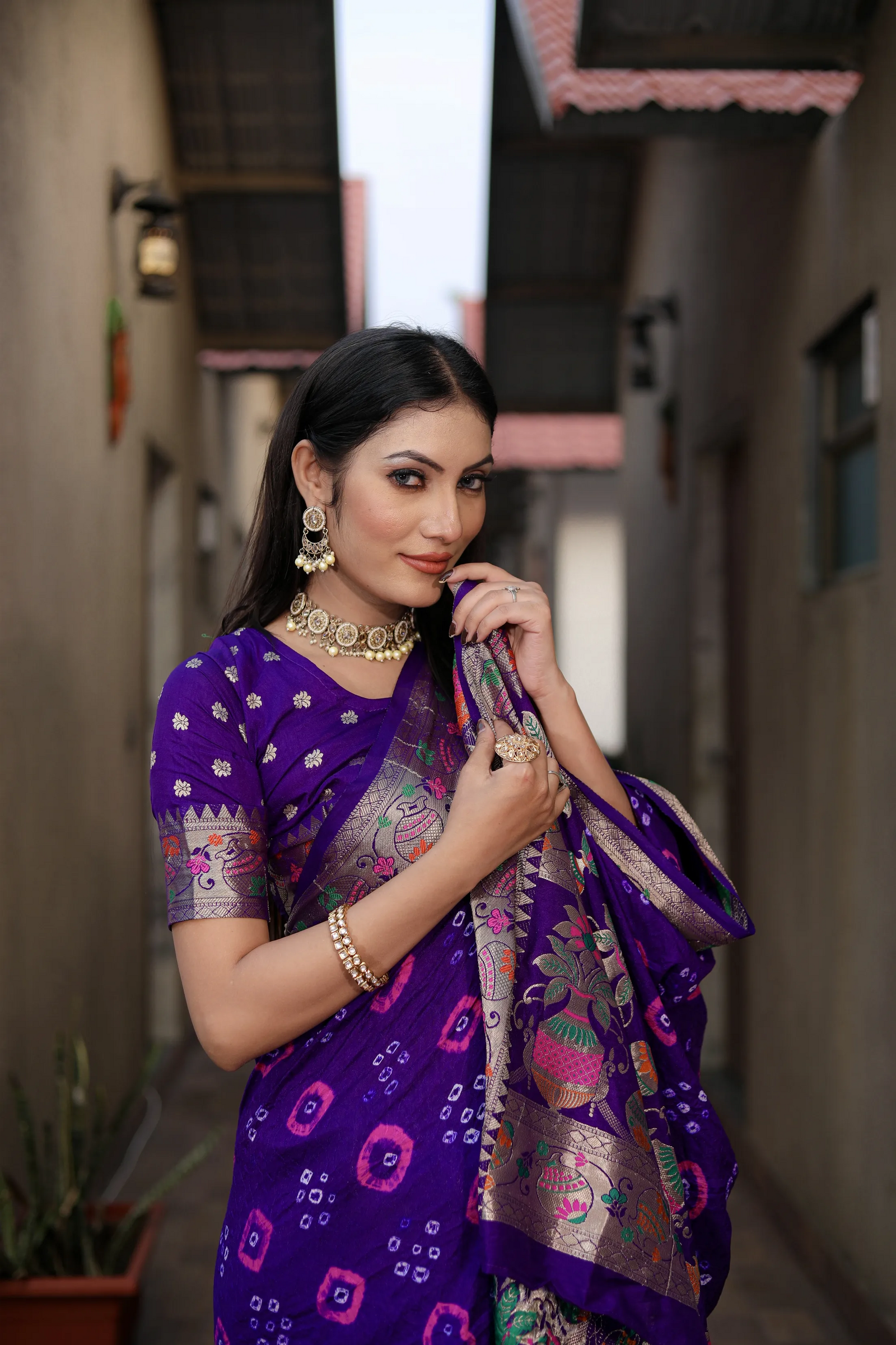 Woman in a purple saree with floral patterns standing in an outdoor setting.