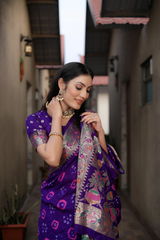 Woman in a purple saree with intricate patterns standing in an alleyway.