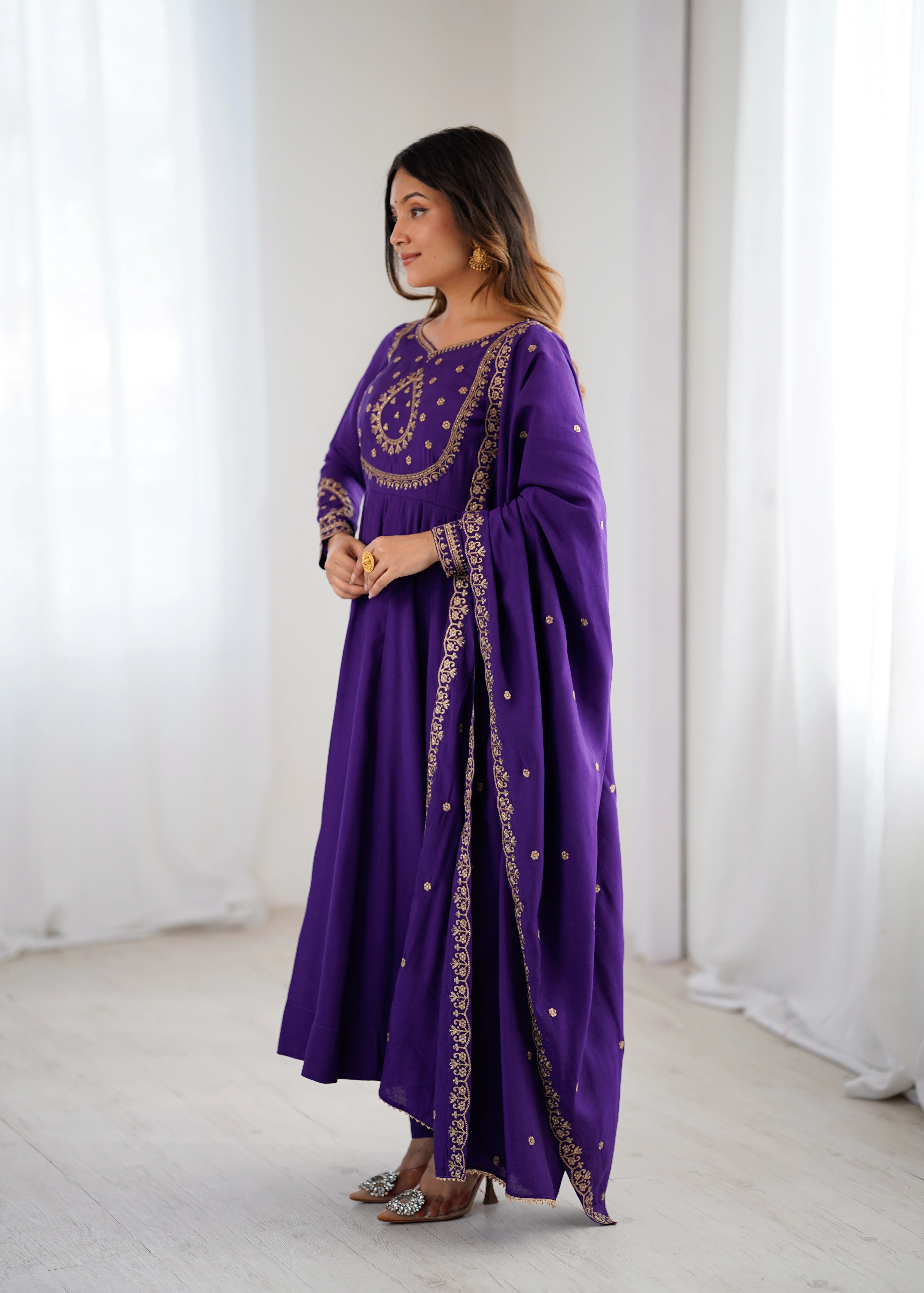 Woman wearing a purple dress with gold embroidery in a minimalistic setting