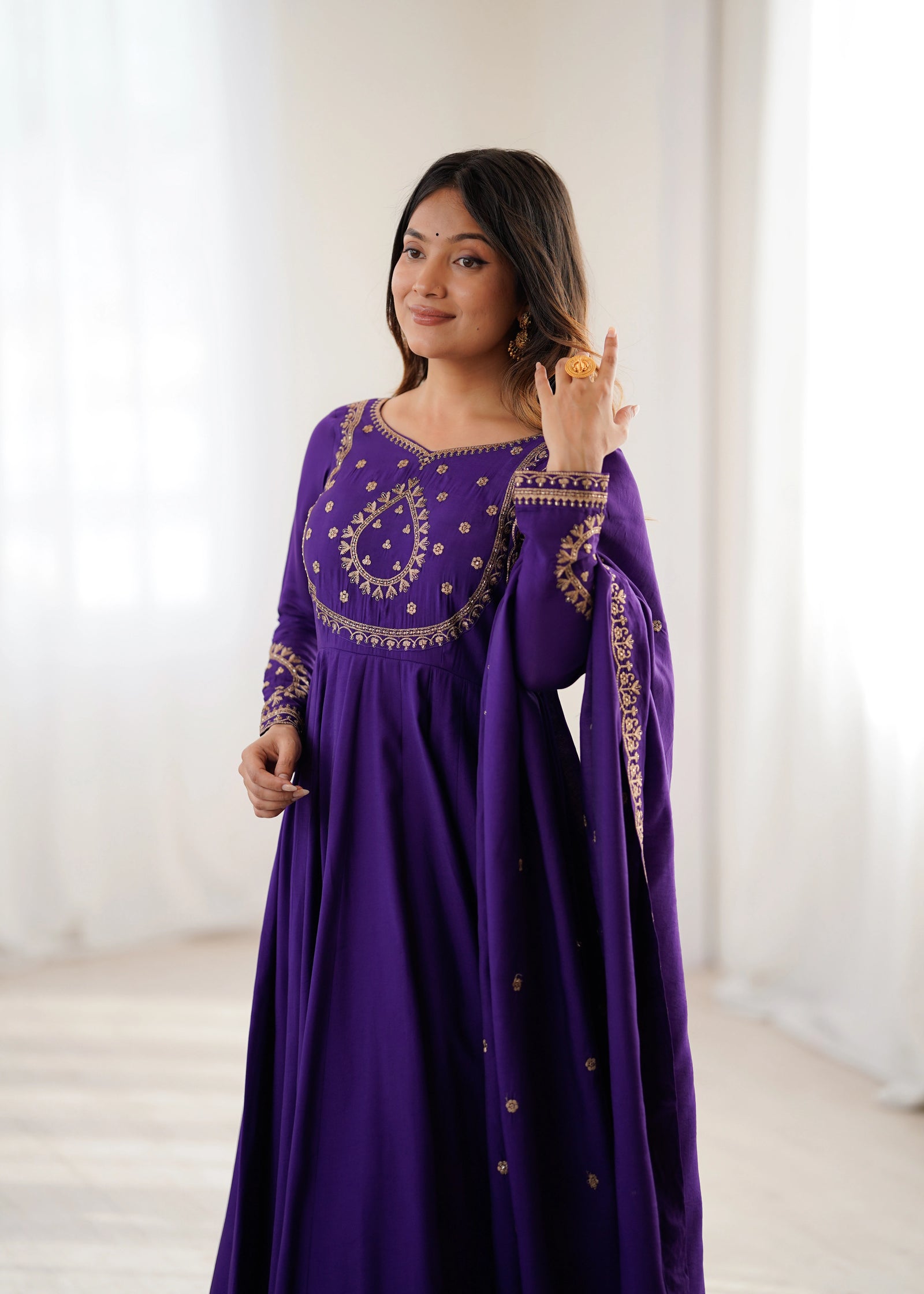Woman wearing a purple embroidered dress against a white background