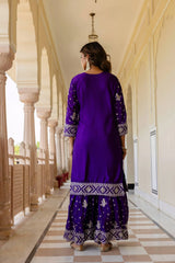 Woman in a purple traditional outfit walking along a corridor with columns.