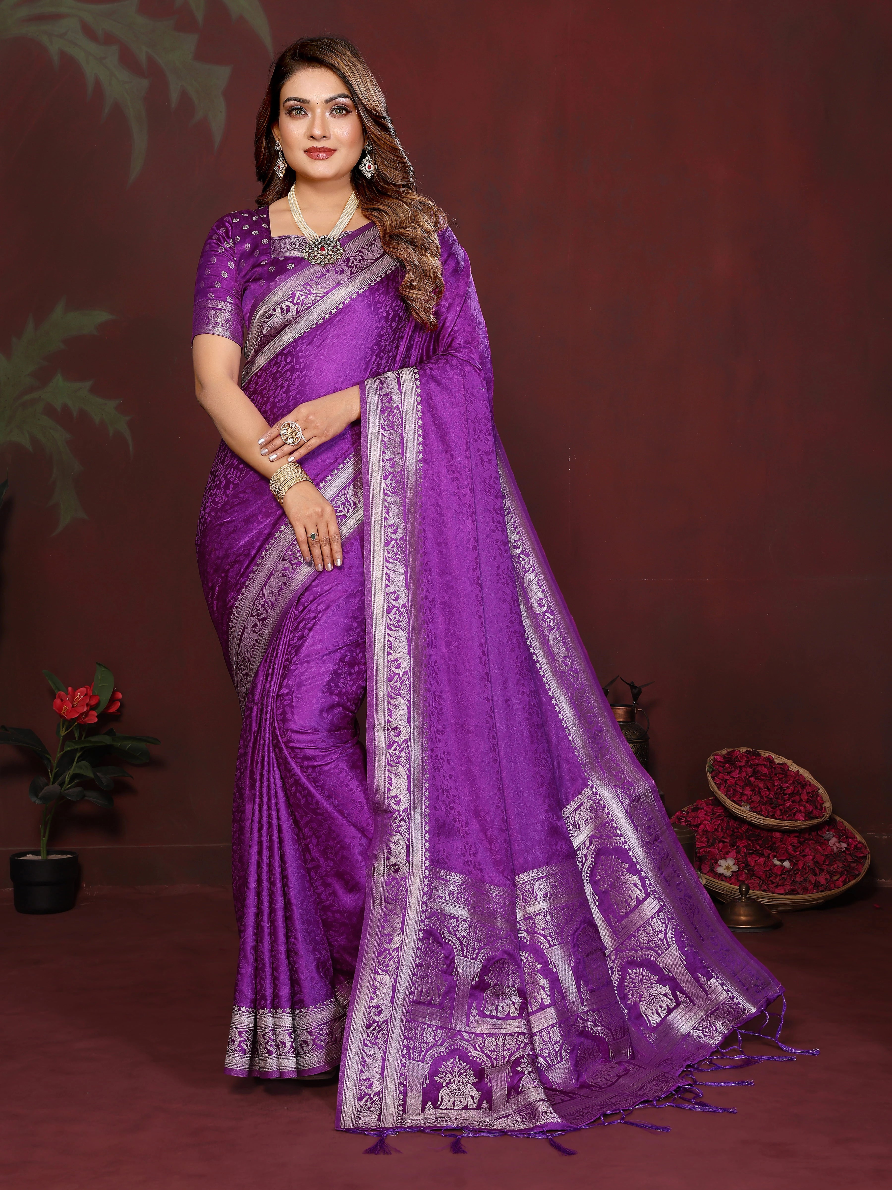 Woman wearing a purple saree with silver border against a dark background