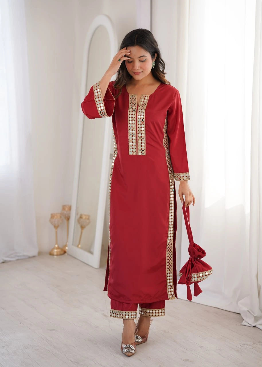Woman wearing a red traditional outfit with gold embroidery in a bright room.