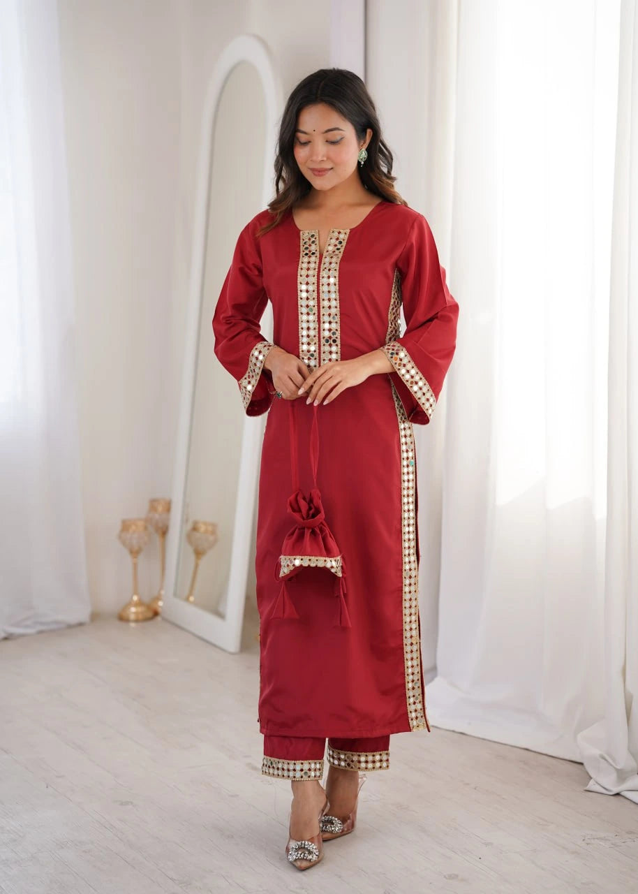 Woman wearing a red traditional outfit with gold embroidery in a white room.