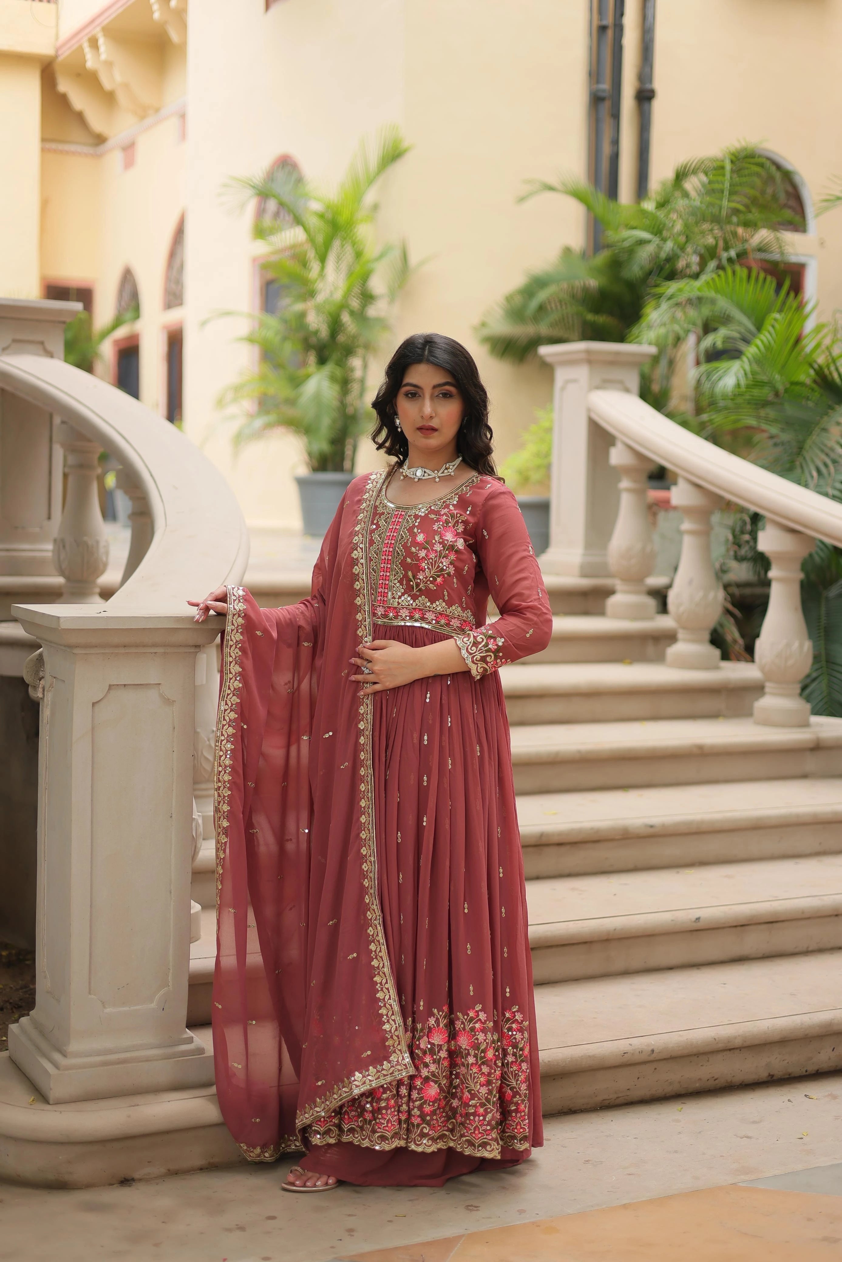 Woman in a traditional outfit standing on a staircase with decorative elements.
