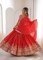 Woman wearing a red embroidered saree with gold details in a minimalistic setting.